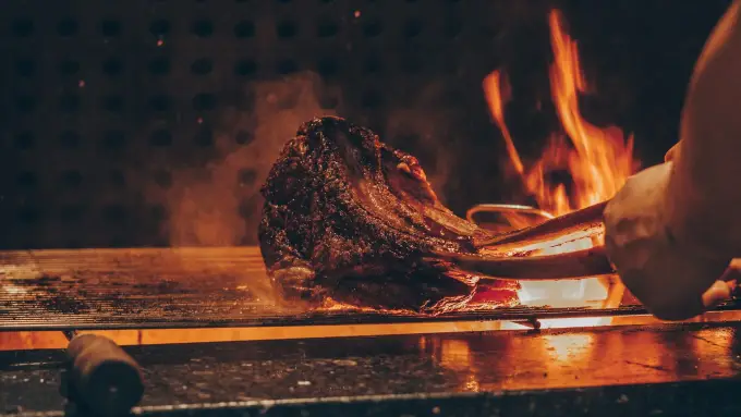 A tomahawk steak over an open flame